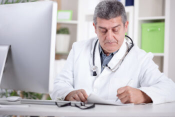 Physician With Stethoscope Around His Neck Working In Office